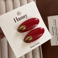 Detailed close-up of retro red oval hair clips with gold Korea lettering and metal frame - Red