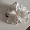 Détail d'un chouchou en organza blanc avec bords argentés et étiquette fashion - Blanc Cassé