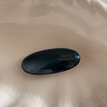 Details einer glänzenden schwarzen ovalen Haarspange mit goldener Aufschrift - Aquamarin