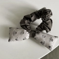 Detail view of the dark grey ruffled fabric and bow design on the retro scrunchie hair tie - Beige Floral Bow