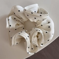 Dettaglio dell'elastico scrunchie in raso bianco a pois con texture a pieghe - crema