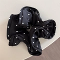 Dettaglio ravvicinato di un elastico in raso nero a pois bianchi su una scrivania - Nero