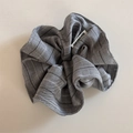 Close-up of a grey striped fabric scrunchie featuring a white label with text - Light Gray Scrunchie