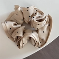 Dettaglio dell'elastico scrunchie in raso champagne con motivo a pois neri classici - Beige