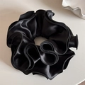 Detail of premium black satin scrunchie with layered ruffle edges and glossy silk texture - Black