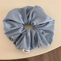 Primer plano de un coletero vaquero azul claro con textura tejida y etiqueta de tela blanca - Azul