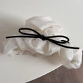 Detail of elegant cream organza scrunchie with a delicate black bow tie decoration - White