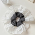 Macro detail of a layered grey and white lace scrunchie featuring a Hand Made textile label - Gray