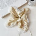 Detailansicht eines champagnerfarbenen Satin-Haargummis mit weißer Spitze und Schleife - Gelbes Quadratisches Tuch-Stil