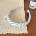 Dettaglio ravvicinato di un cerchietto in tessuto a righe blu e bianche su legno - Strisce Diagonali