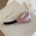 Vue détaillée d'une pince banane en satin vieux rose avec étiquette dorée sur un livre - Rose