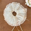 Détail de chouchou en dentelle à pois beige avec ruban rose sur bois sombre - Chouchou Bordure Rose