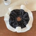 Makro-Detail eines übergroßen Blumen-Scrunchies mit Paisley-Netz auf Holzuntergrund - Schwarz