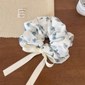 Détail d'un chouchou floral avec ruban crème sur une surface en bois avec des accessoires - Floral Crème