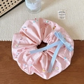 Detailed close-up of pink scrunchie with colorful beads and a blue ribbon bow decoration - Pink