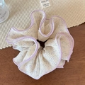 Détail d'un chouchou en dentelle florale avec bordure violette et texture en mousseline - Bordure Violette