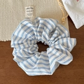 Détail du chouchou à rayures bleues et blanches sur bois foncé avec des accents de lin - Rayé