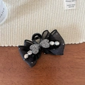 Detail of black bow hair claw with sparkling crystal hearts and rhinestones on soft mesh fabric - Black