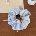 Primer plano de coletero floral azul claro con cintas en una mesa de madera rústica - Estampado de Mariposa / Coletero Estilo Cintura Azul