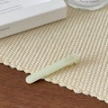 Detail einer cremefarbenen Acetat-Haarklammer mit Goldaufdruck auf einer weichen Matte - Milchweiß