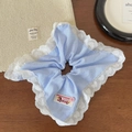 Détail d'un chouchou à rayures bleues avec bordure en dentelle cœur et étiquette tissée - Rayé Bleu