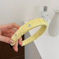 Détail d'un serre-tête en satin jaune avec perles et cristaux en forme de fleurs - Jaune