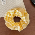 Vue détaillée du chouchou à carreaux jaune et blanc avec broderie cerise sur bois - Chouchou Jaune