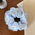 Gros plan sur un chouchou en maille bleu clair avec dentelle sur table en bois vintage - Bleu Maille Quatre Couches