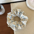 Detail eines gelb-blau karierten Haargummis mit flauschiger Textur auf Holztisch - Gelb-Blau gestreift