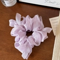 Macro shot of a lavender organza scrunchie with long ribbons on a dark wooden background - Purple