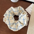 Detalle de un scrunchie a cuadros con encaje sobre fondo de madera y accesorios - Rayas amarillas y azules