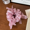 Detailed macro view of soft pink organza scrunchie with ribbons on a rustic wooden table - Pink