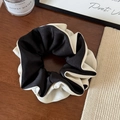 Detail eines großen schwarz-weißen Satin-Haargummis mit luxuriöser Seidentextur und Falten - Schwarz Color Block