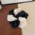 Dettaglio di un elastico in raso a contrasto bianco e nero su tavolo in legno scuro - Bianco e Nero