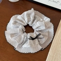 Detail of grey checkered scrunchie with black wavy edges and a delicate ribbon bow - Coffee Striped Scrunchie