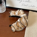 Dettaglio del fermaglio a banana in raso champagne con strass su tavolo di legno - Clip a Banana Beige