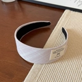 Detail view of a wide pleated headband in lavender fabric with a stylish woven label - Pink Striped Headband