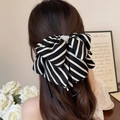 Elegant zebra stripe bow hair claw clip with pearl embellishment on model hair - Black Stripe
