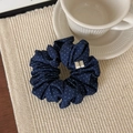 Detail eines dunkelblauen Polka-Dot-Stoff-Haargummis auf beiger Matte mit Kaffeetasse - Marineblaue Punkte