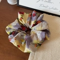 Detail view of oil painting style floral scrunchie on fabric and wooden background - Scrunchie