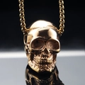Detailed macro view of a golden skull pendant with polished finish on black mirror surface - Pendant Only (No Chain) / Rose Gold