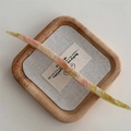 Dettaglio della forcina in acetato francese con trama marmorizzata e logo inciso - Rosa Verde Cangiante