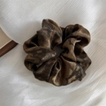 Detail view of large silk-textured scrunchie with dark brown and black ink-wash dye pattern - Brown