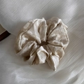 Detail of champagne satin scrunchie showing pleated silk texture and elegant metallic luster - Off-white