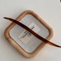 Dettaglio di un fermaglio per capelli in acetato tartarugato con logo dorato - Caffè Profondo Iridescente