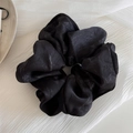 Detail van vintage zwarte satijnen scrunchie met inkttextuur en elegante stofplooien - Zwart