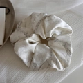 Detailweergave van de inktmarmeren textuur op de satijnen stoffen oversized scrunchie - Broken Wit