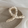 Dettaglio del fermaglio per capelli in tessuto a pois su un vassoio da esposizione in ceramica - Design a Torsione (FJ892715) / Bianco