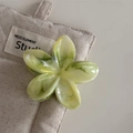 Gros plan d'une pince à cheveux fleur en acétate marbré vert sur tissu beige - Marbre Vert Frais