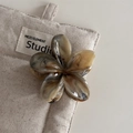 Detail einer marmorierten Haarklammer in Blumenform auf einem minimalistischen Leinenbeutel - Kaffeebrauner Marmor